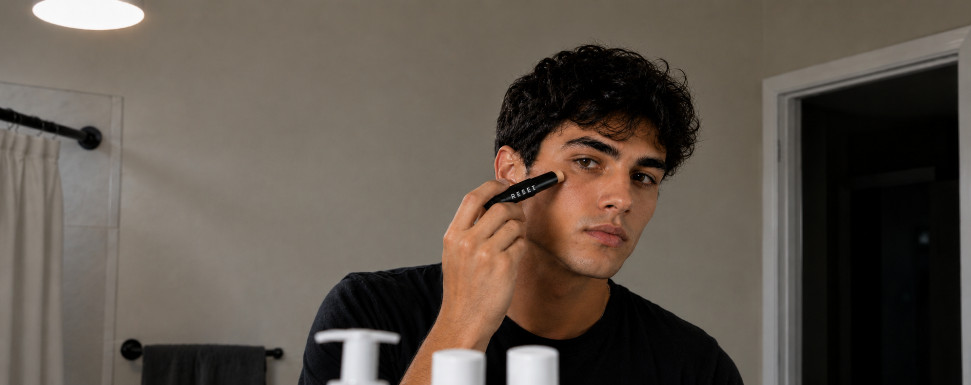 Man applying Reset Spot Corrector Pen in bathroom mirror